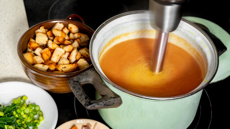 Immersion blender in pot of soup