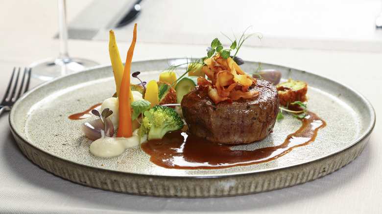 a plate of filet mignon set on the tabletop at a high-end restaurant