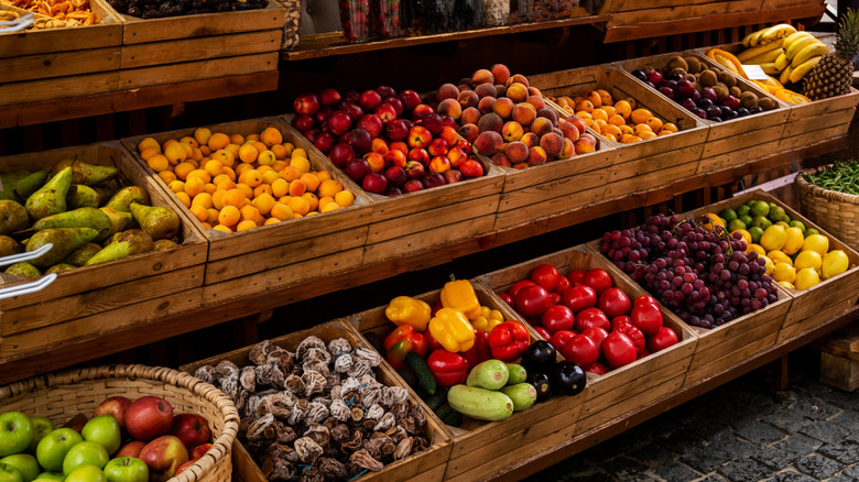 Assortment of colorful fresh fruits and vegetables displayed in wooden crates and baskets