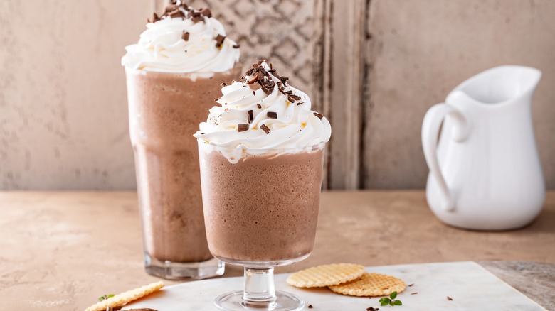 Two blended coffee drinks with whipped cream on a table