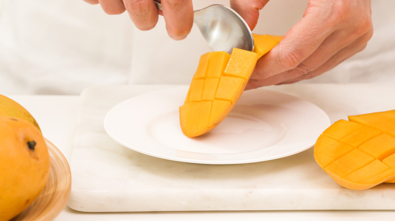 Person slicing mango with spoon
