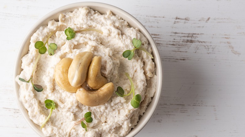 Cashew cream cheese topped with cashews and herbs