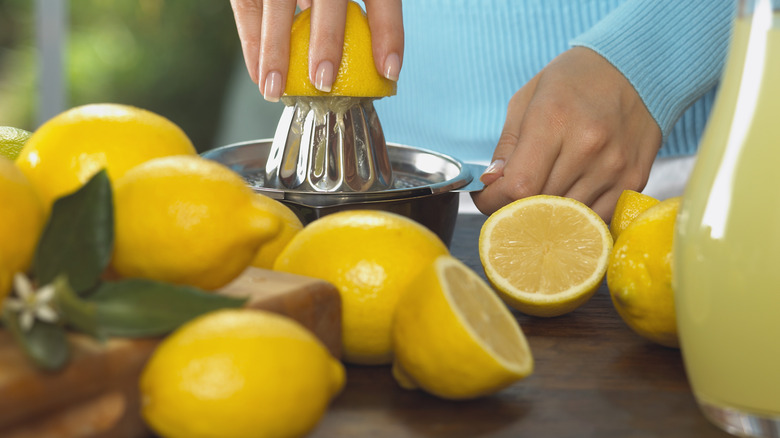 Hands juicing lemons on countertop