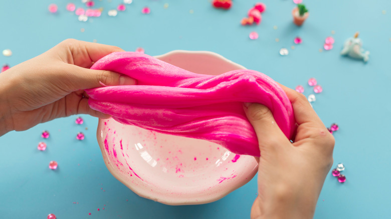 Hot pink slime being stretched by two hands