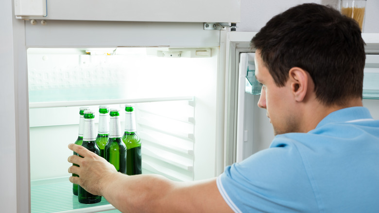 man putting beer in fridge