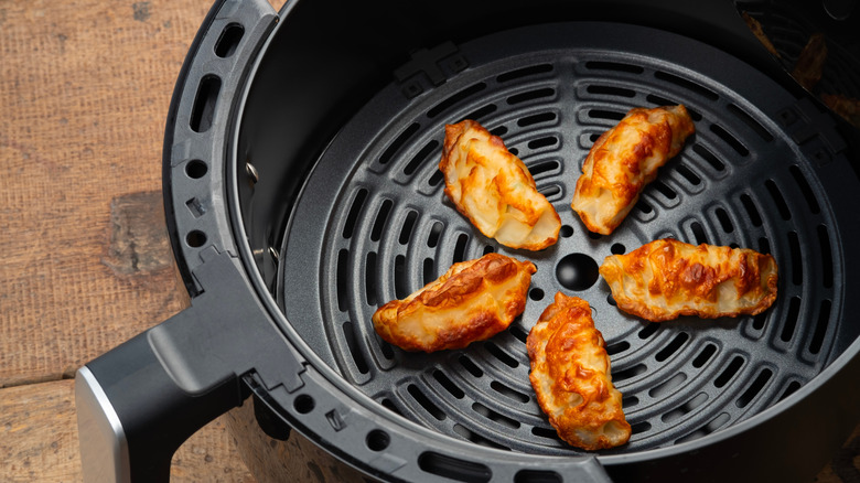 Crispy potstickers in air fryer basket.