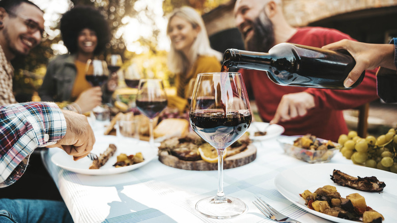 wine being poured at a barbecue dinner outdoors