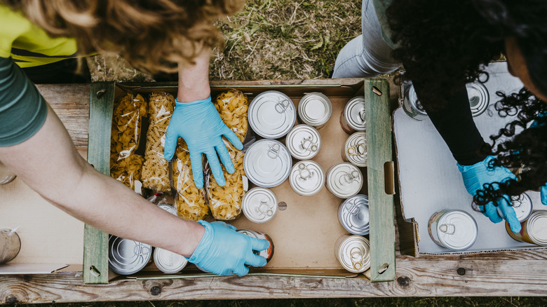 People packing a box with canned and dry goods