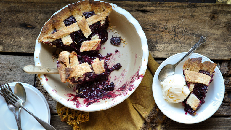 slice of huckleberry pie with ice cream on a rustic background