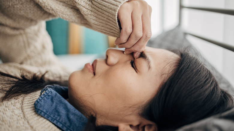 woman holding nose in pain