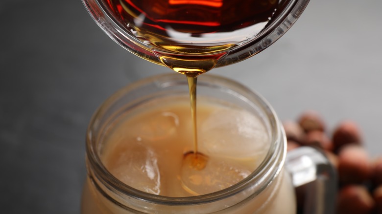 syrup being poured into iced coffee