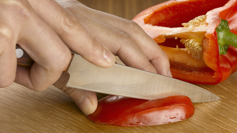 person slicing red peppers