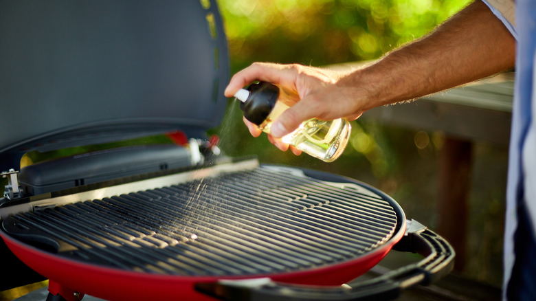 Hand spraying a grill with cooking spray