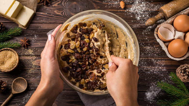 person mixing raisins into batter