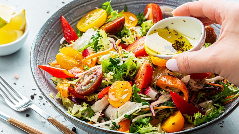 Person pouring tadka over salad