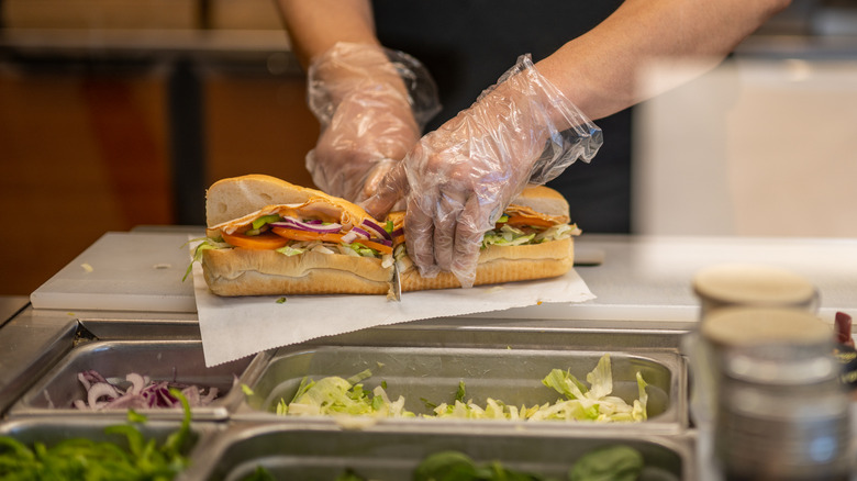 sandwich artist cutting footlong sub