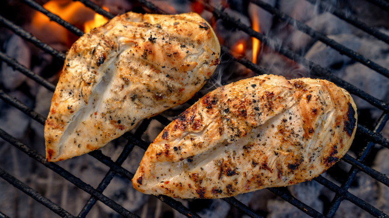 Cooking chicken breasts over charcoal