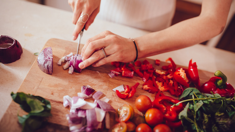 Hands chopping vegetables on cutting board