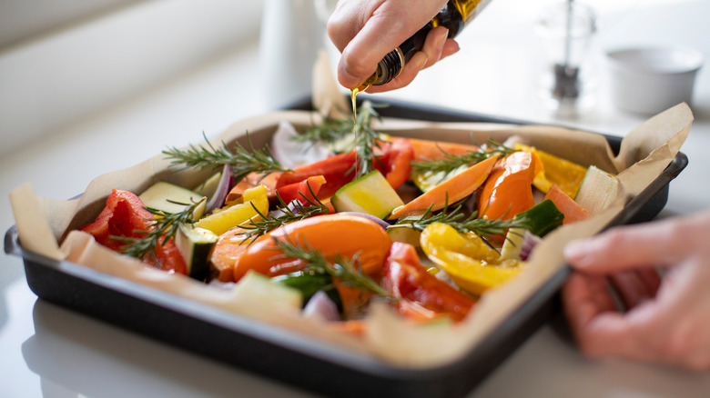 Person pouring oil on vegetables