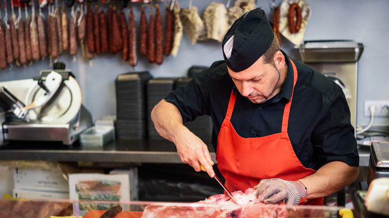 butcher trimming piece of meat