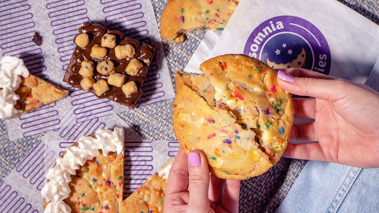 Woman breaking Insomnia's confetti party cookie in half