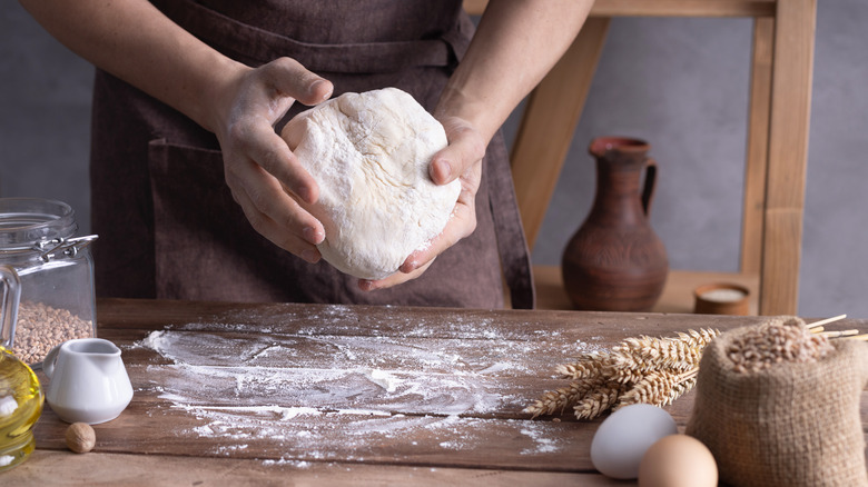 man handling dough over a wooden table