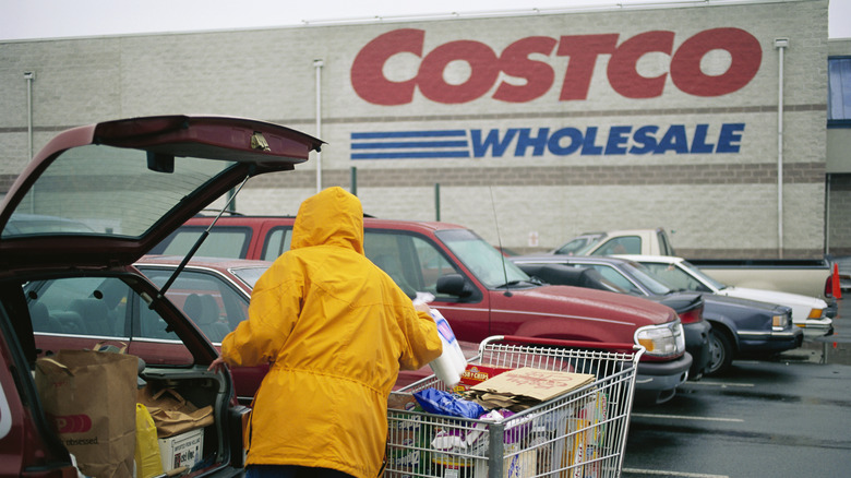 shopper loading trunk with groceries in front of costco