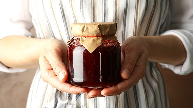 Hands holding pureed fruit in jar 