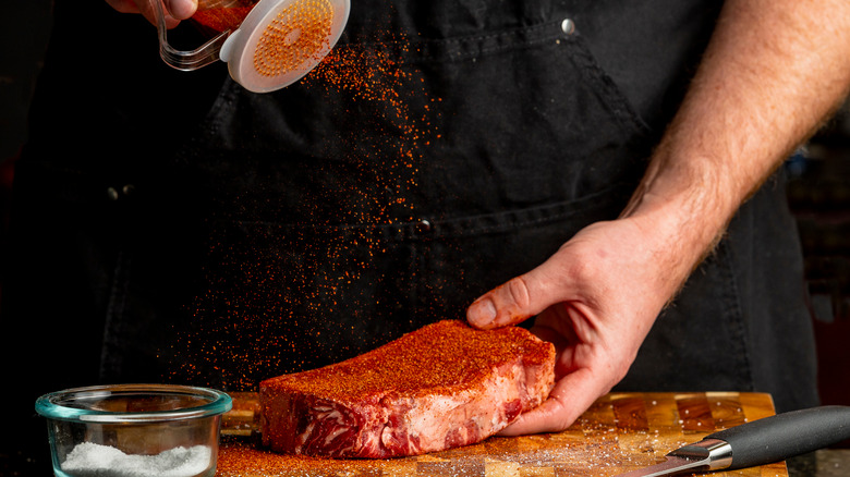 seasoning steak on a cutting board