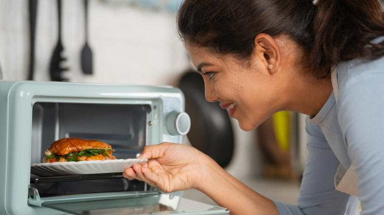 Woman putting a sandwich in the microwave