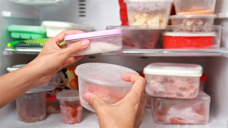 Hands holding frozen food containers 