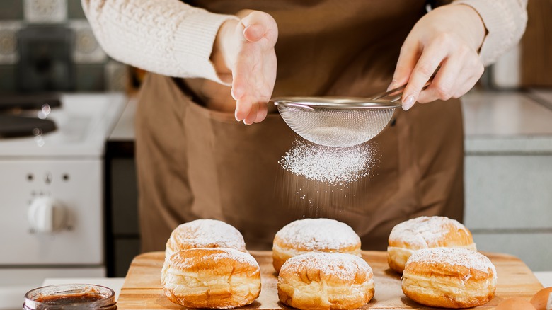 Donuts being dusted with powdered sugar