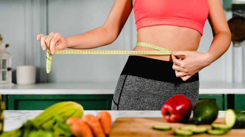 woman with vegetables measuring waist