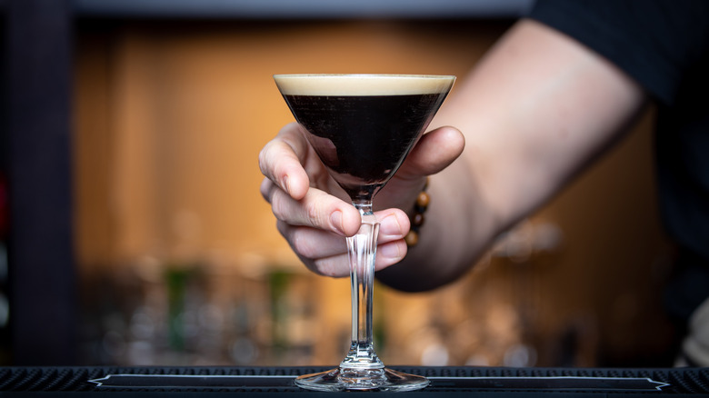 Person holding a glass of dark liquid