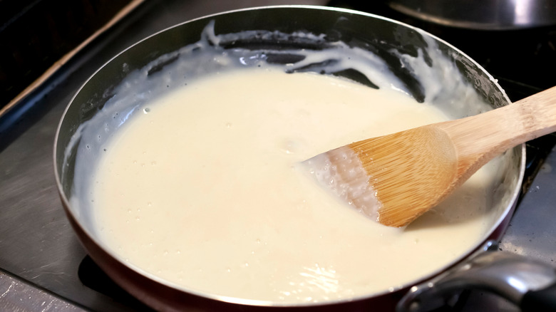 cooking béchamel sauce in pan on stove