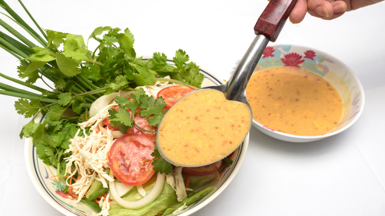 person spooning dressing onto salad