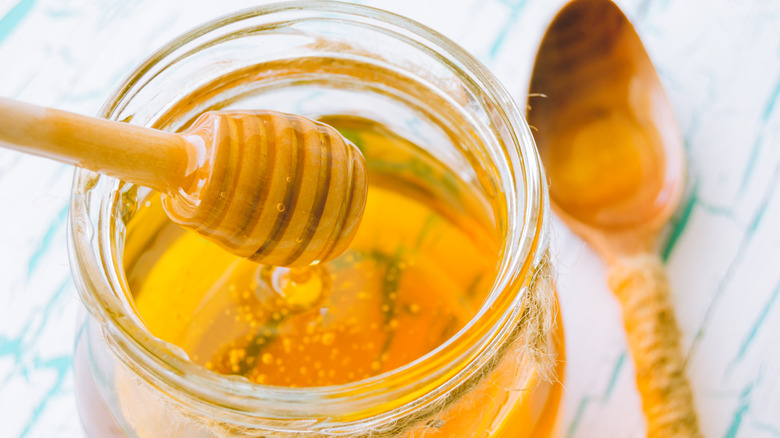 Honey on a wooden honeycomb in glass jar