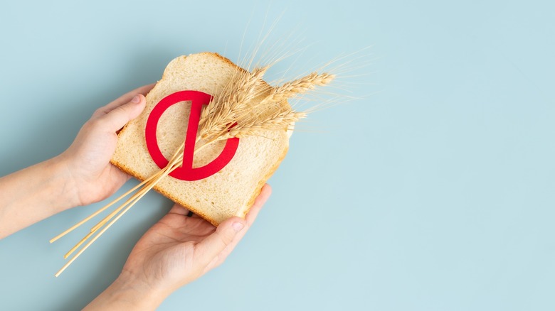 hands holding slice of bread with no-gluten symbol