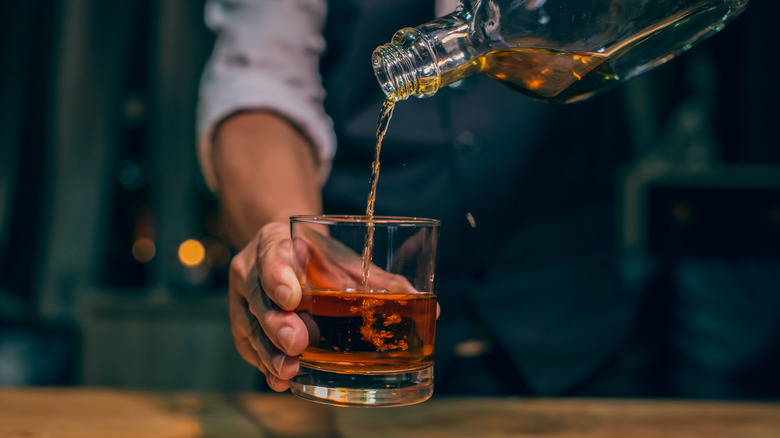 bartender pouring whiskey into glass