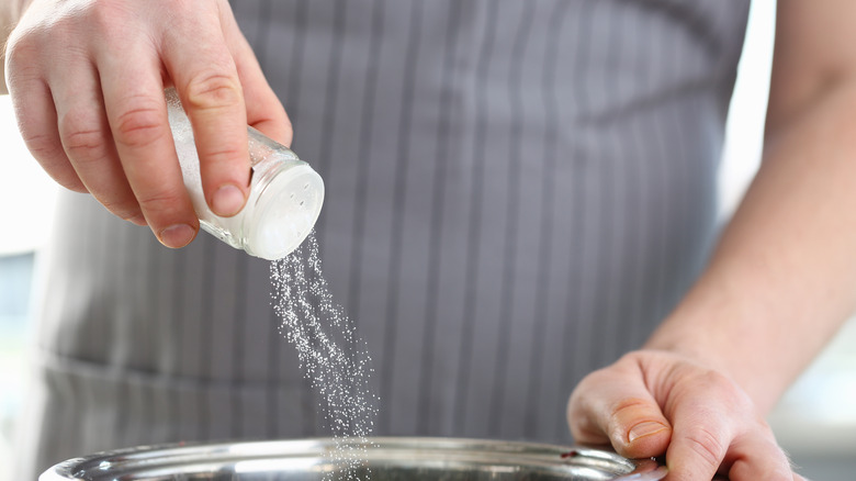 Person seasoning food with salt