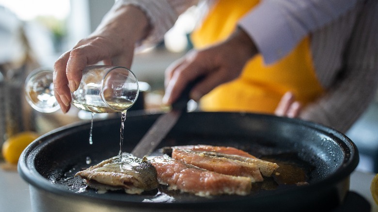 Couple pouring wine onto fish