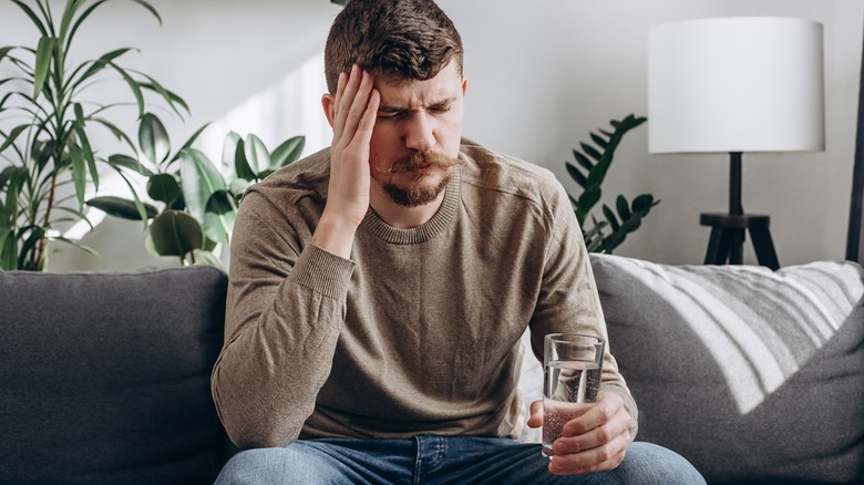 hungover man holding glass of water