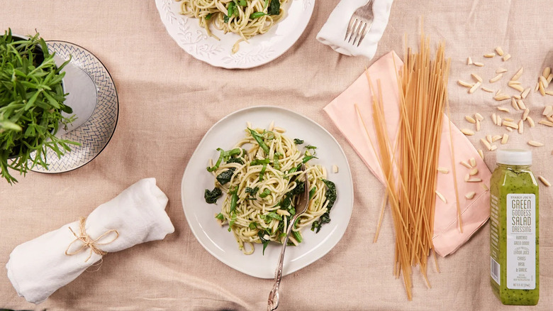 Plate of pasta on a table with a bottle of dressing