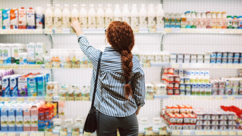 A woman reaches for milk at a grocery store