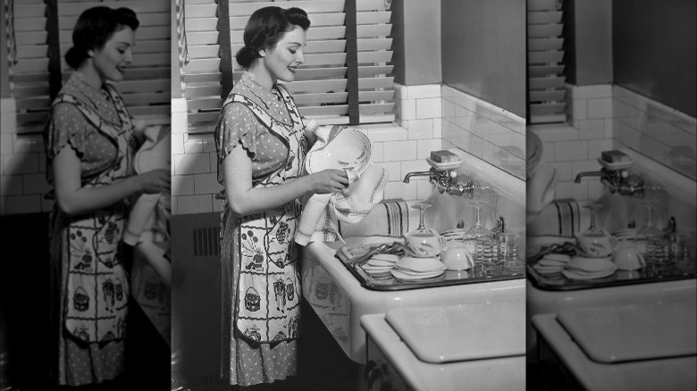 Apron wearing person washing dishes