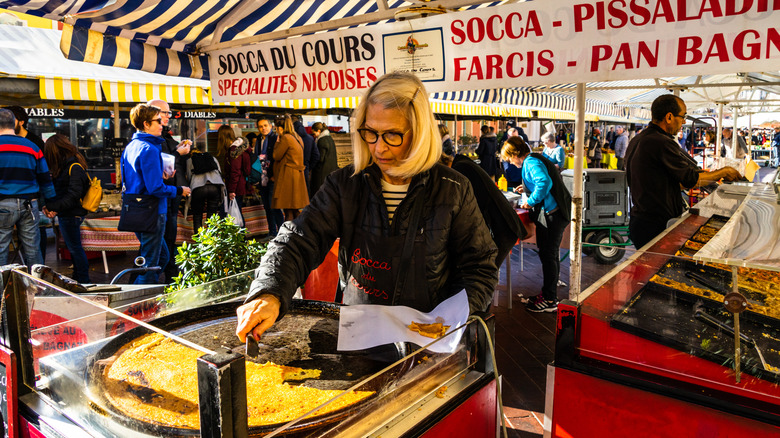 woman in France slicing socca