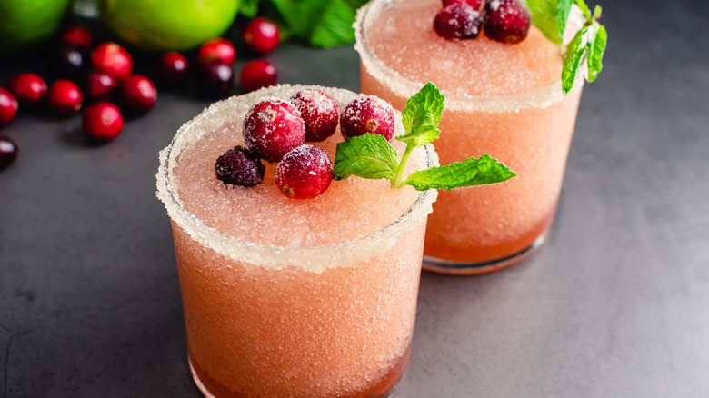 A frozen cranberry margarita in a rocks glass top with cranberries.