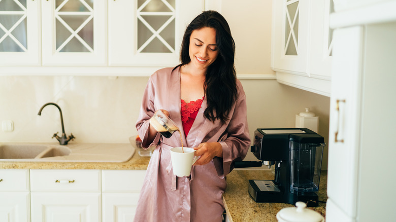 Woman in kitchen pouring a cup of coffee