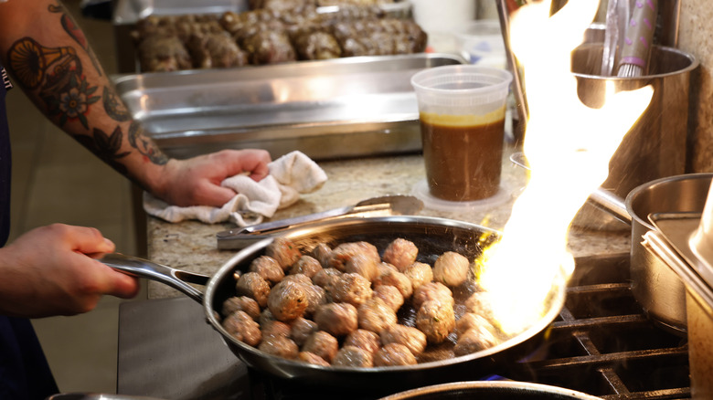 Chef searing meatballs over flames