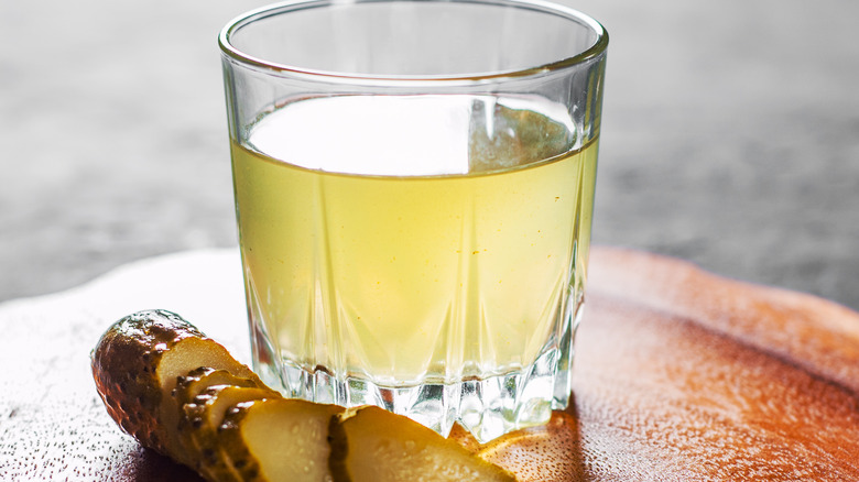 Pickle juice in clear glass next to sliced pickles